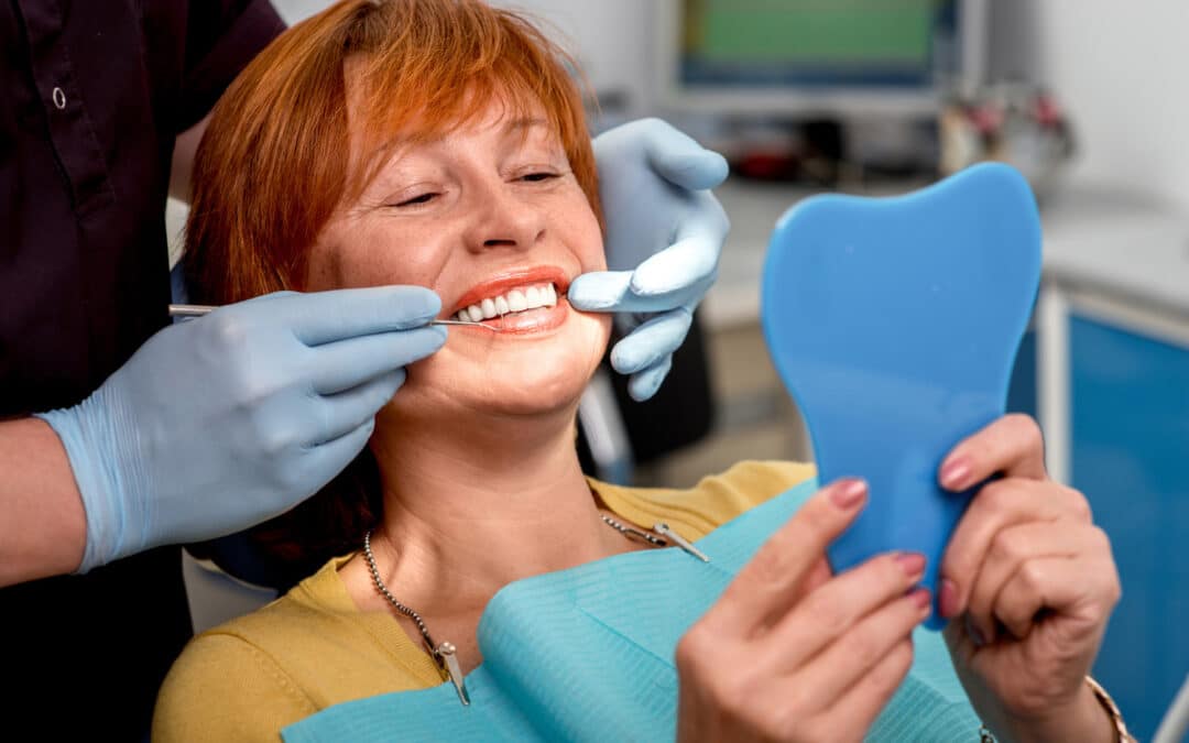 Woman at the dentist looking at her new smile with dental implants in Richmond VA